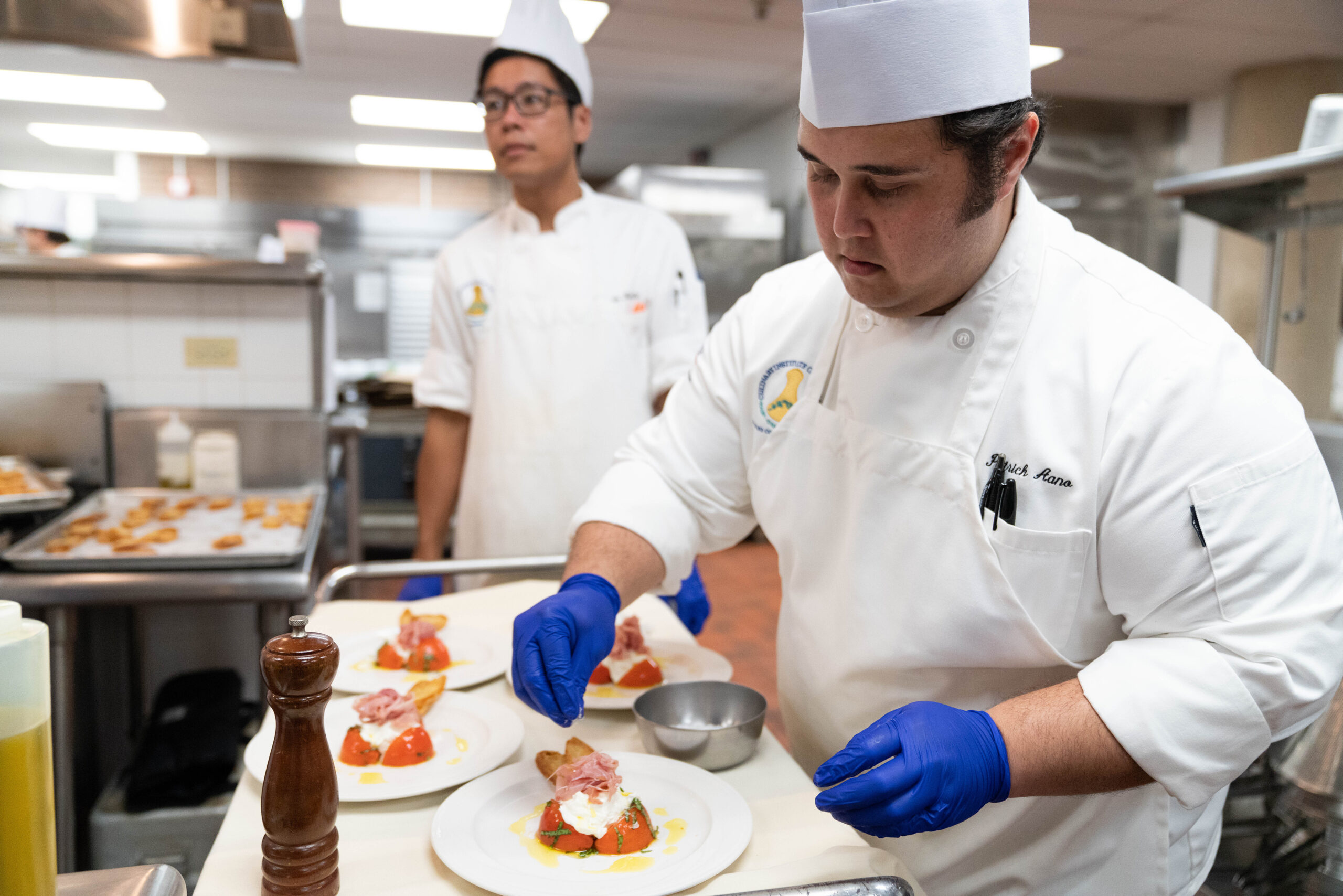 Male culinary student finishing up plating an appetizer.